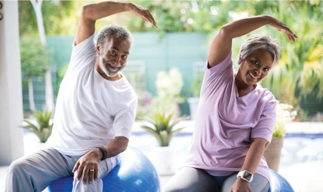Two active adults stretching together outdoors as part of their physical therapy program